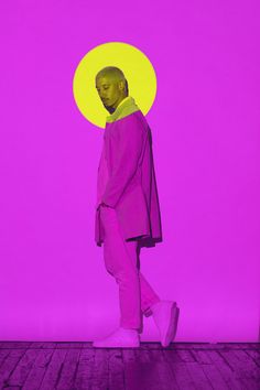 a man standing in front of a purple and yellow background with his head turned to the side