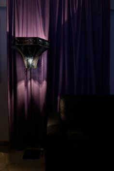 a room with purple curtains and a black couch