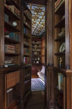 the inside of a wooden bookcase with many books on it's shelves and an ornate ceiling