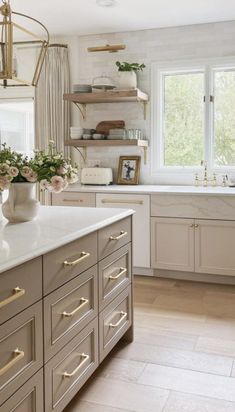 a large kitchen with lots of counter space and flowers in vases on the island