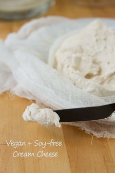 a spoon with some cream on it sitting on top of a wooden table next to a napkin