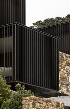 two black buildings with stone walls and trees in the background