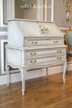 an antique white dresser with mirror and chair in front of it on hardwood flooring