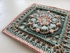 a crocheted square is sitting on a table with a flower motif in the center