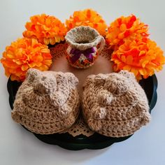 two crocheted baby booties sitting on top of a doily with orange flowers