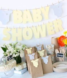 a baby shower is set up on a table with paper bags and flowers in vases