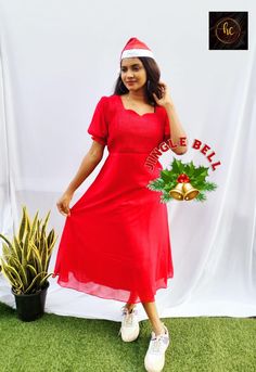 a woman in a red dress and santa's hat standing next to a plant