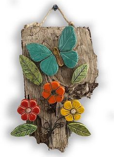 a piece of wood with flowers and leaves painted on the side, hanging from a rope