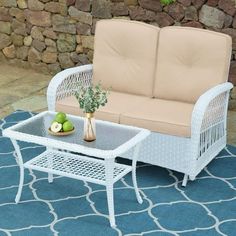 a white wicker couch sitting on top of a blue rug