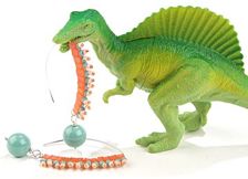 a green toy dinosaur with beads around it's neck