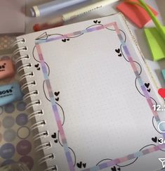 an open notebook with hearts on it next to markers and pens