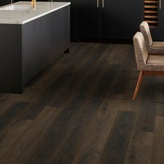 a kitchen with dark wood floors and black cabinets