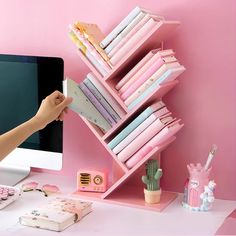 a pink desk with a computer and bookshelf