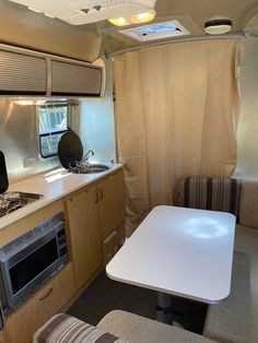 a kitchen and living room inside an rv with beige curtains on the windowsills