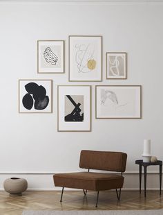 a living room with pictures on the wall and a chair in front of an ottoman