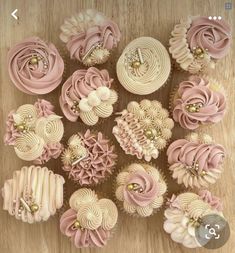 cupcakes with pink frosting and gold decorations on a wooden table, top view