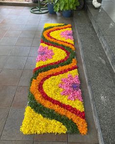 a long flower arrangement on the ground in front of a planter filled with flowers