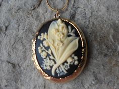 "Beautiful cameo locket The cameo is a gorgeous lily of the valley on your choice of backgrounds, green, lavender/purple, and black, also hand painting is available The gold plated locket is victorian style with beautiful etching on both the front and back, measuring 2\" long. It can hold two photos and/or treasured keepsakes Pass down from generation to generation The chain is 22\" 1.2mm gold plated snake chain with a lobster claw clasp Perfect for brides or bridal parties. Makes a unique memor Flower Shaped Locket Necklaces For Weddings, Flower Shaped Locket Jewelry For Wedding, Floral Wedding Locket Jewelry, Flower Shaped Wedding Locket Jewelry, Wedding Flower Locket Jewelry, Cameo Medallion Locket Necklace For Weddings, Antique Flower Necklaces For Weddings, Fairytale Jewelry, Backgrounds Green