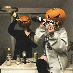 two people in halloween costumes drinking wine and holding jack - o'- lantern pumpkins