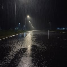 an empty street at night with lights on and rain coming down from the sky over it