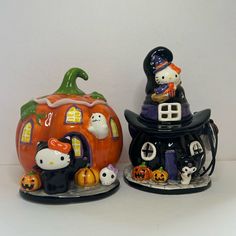 two ceramic pumpkins with hello kitty figures on them, one has a ghost and the other has a cat