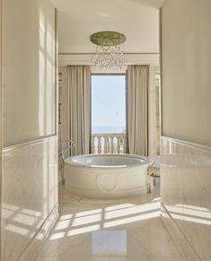 a large white bath tub sitting in the middle of a bathroom next to a window