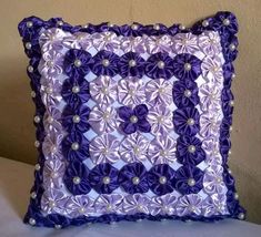 a purple and white decorative pillow on a bed with pillows in the shape of flowers