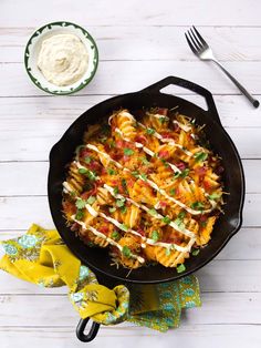 a skillet filled with pasta covered in sauce and garnished with parsley