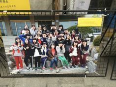 a group of young people posing for a photo in front of a building on the street