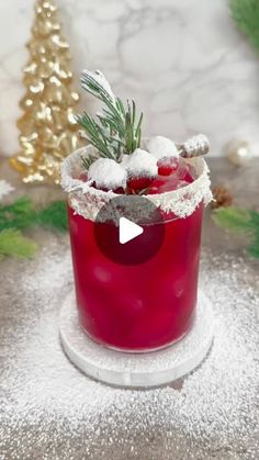 a red cocktail in a glass with a pine sprig garnish on top