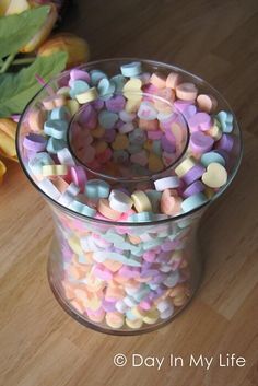 a jar filled with candy sitting on top of a wooden table next to some flowers