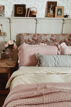 a bed with pink comforter and pillows in a bedroom next to a wooden table