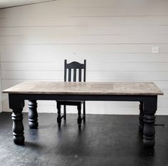 a wooden table with two chairs next to it on a black floor in front of a white wall