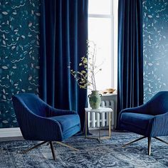 two chairs in front of a window with blue curtains and floral wallpaper on the walls