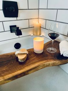 a bathtub with a candle, soap and wine glass on the counter next to it