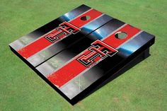 two red and black cornhole game pieces sitting on top of a green grass covered field