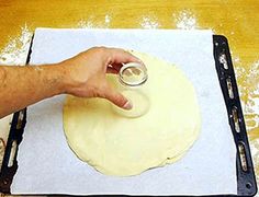 a person is kneading dough on top of a sheet of waxed paper