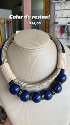 a necklace with blue beads is displayed on a mannequin