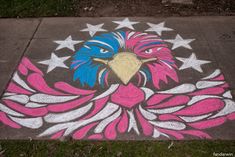 an eagle painted on the sidewalk with stars and stripes around its head in pink, blue, and white colors