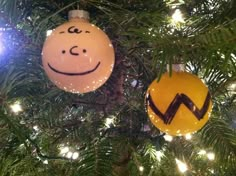 two ornaments hanging from a christmas tree decorated with smiley faces and words written on them