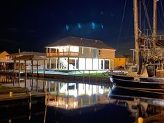 a sailboat is docked in the water near some houses at night with lights on