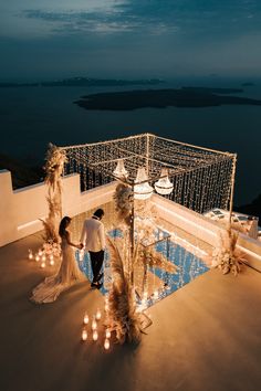 a bride and groom standing on the roof of a building with candles in front of them