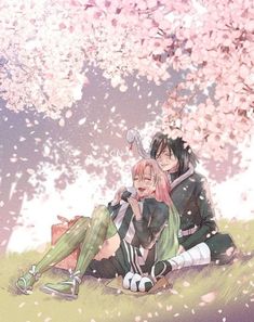 two people sitting on the ground under a tree with pink flowers and petals around them