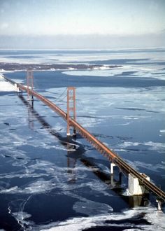 an aerial view of a bridge in the middle of water with ice floating around it