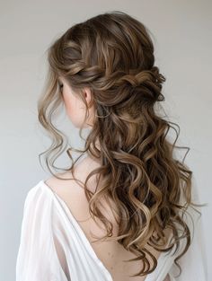 a woman with long hair in a half updo is wearing a white shirt and has her back to the camera