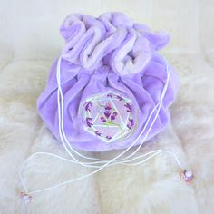 This lavender multi pocket dice bag is made with two shades of purple plush fabric. It is soft to the touch and will keep your dice nice and cozy. The embroidered design on the front features a D20 with swirling blooms of lavender surrounding it. The bag has strong cord drawstrings accented with purple butterfly charms at the ends. Inner bag space is about 9 x 4.5 inches, plenty of room for several sets of dice, there are 6 inner pockets that will hold 3 to 4 standard dice sets and 1 large middl Purple Embroidered Bag For Gift, Handmade Purple Bags For Gifts, Handmade Purple Bags As Gifts, Dice Collection, Fabric Butterfly, Purple Bag, Dice Bag, Plush Fabric, Purple Butterfly