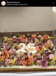 a cake decorated with flowers and the number twenty five is in a cardboard box on top of a table