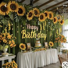 a birthday party with sunflowers and greenery on the wall, table cloth