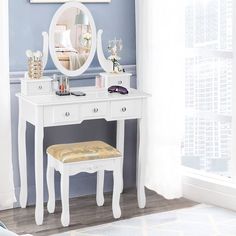 a white dressing table with a mirror and stool