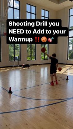 a young boy holding a basketball on top of a hard wood floor in an indoor gym